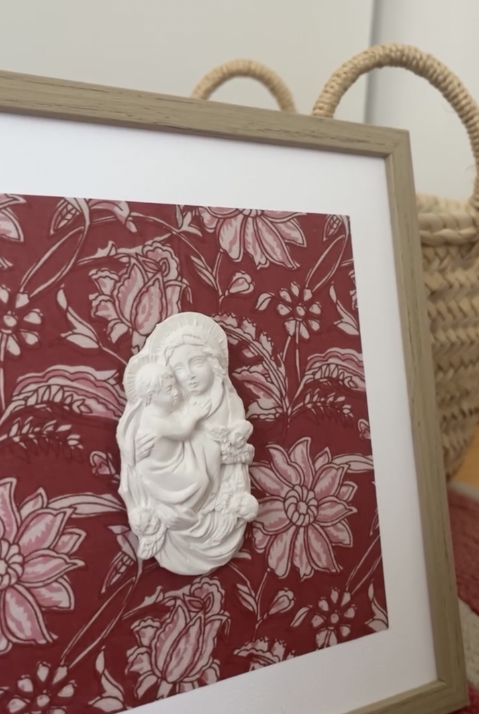 Figura de escayola Virgen con Niño sobre fondo granate floral, enmarcada